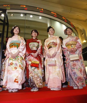 Women dressed in ceremonial kimonos pose in front of a board showing stock prices at the Tokyo Stock Exchange's (TSE) New Year opening ceremony in Tokyo January 5, 2009.[Xinhua/Reuters]
