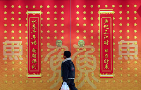 A citizen walks by a large poster of spring couplet on a street of Nanjing, capital of east China's Jiangsu Province, Jan. 2, 2009. Different kinds of festive posters appeared along streets of Nanjing as Spring Festival approaches, making the historic city quite beautiful. [Wang Xin/Xinhua] 