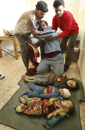 A Palestinian man reacts in front of the bodies of three children killed by an Israeli tank shell, one of them his son, at Shifa hospital in Gaza Jan. 5, 2009. [Xinhua]