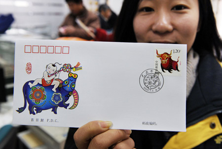 A postal official shows the first day cover of a stamp marking the Chinese traditional lunar Jichou Year of 2009 at a post office in Qingdao, east China's Shandong Province on Jan. 5, 2009. [Xinhua]