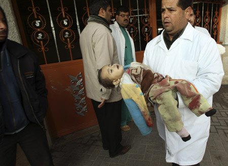 A Palestinian doctor carries the body of a child killed by an Israeli tank shell, at Shifa hospital in Gaza Jan. 5, 2009. An Israeli tank shell killed three Palestinian children in their home in eastern Gaza City on Monday, medical officials said. They said several other Palestinians were wounded in the incident in Gaza's Zeitoun neighbourhood. An Israeli military spokeswoman said she was checking the report. [Xinhua]