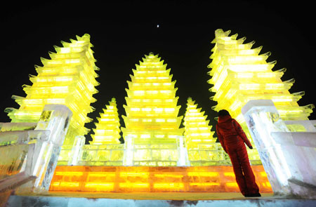 A tourist stands before ice carvings at the Harbin Ice and Snow World in Harbin, capital of northeast China's Heilongjiang Province, Jan. 5, 2009. The 25th Harbin International Ice and Snow Festival of China was opened on Monday at the local park in Harbin, capital of northeast China's Heilongjiang province, featuring ice and snow art, sports, trade and tourism.[Wang Jianwei/Xinhua]