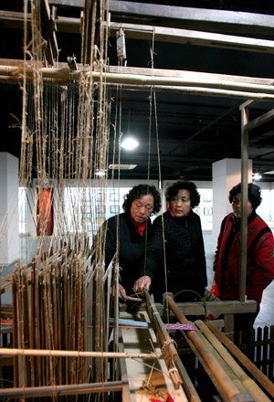 Visitors try an ancient textile machine in newly opened Shanghai Textile and Raiment Museum in Shanghai, China, on Jan. 5, 2009. (Xinhua Photo)