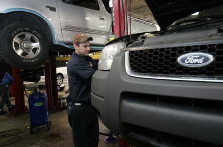 Auto mechanic Paul Cook works on a customer's Ford Escape SUV in the service department of a Ford car dealership in Warren, Michigan Dec. 18, 2008. [Xinhua/Reuters]
