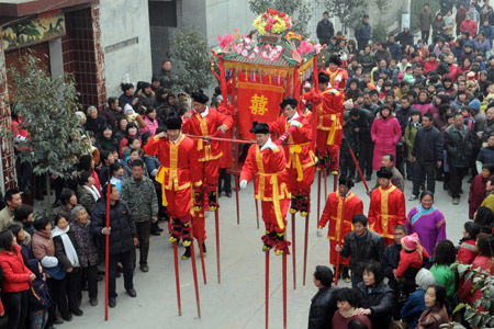 The bride sits in the sedan, carried by people in traditional costume walking on stilts, during a wedding in the Chinese traditional style held at Wannan Village of Qinyang City, central China's Henan Province, Jan. 6, 2009.