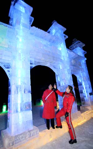 A tourist (R) takes pictures of the ice sculpture with her mobile phone as her friend looks on during the 4th Ice, Snow, Cultural and Tourism Festival in Barkol Kazak Autonomous County, northwest China's Xinjiang Uygur Augonomous Region, Jan. 5, 2009.