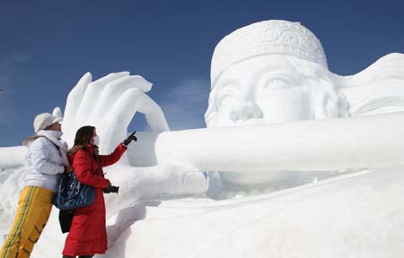 Two tourists view snow sculpture 'Shepherdess' during the 4th Ice, Snow, Cultural and Tourism Festival in Barkol Kazak Autonomous County, northwest China's Xinjiang Uygur Augonomous Region, Jan. 5, 2009. 