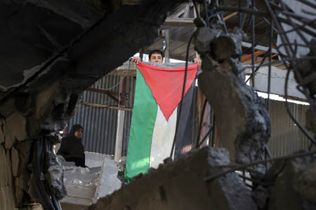 A Palestinian boy waves a Palestinian flag on rubbles after an Israeli airstrike in Rafah, southern Gaza Strip, Jan. 6, 2009. Israeli Prime Minister Ehud Olmert on Tuesday rejected a European Union (EU) request for a 48-hour ceasefire in the Gaza Strip, vowing to push ahead the offensive in the Gaza Strip till security is restored to southern regions of Israel. [Wissam Nassar/Xinhua] 