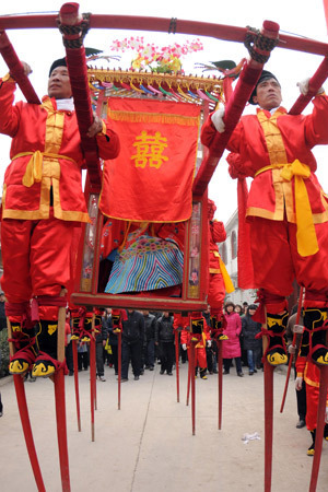 A bride sits in a sedan, carried by people in traditional costume walking on stilts, during a wedding in the Chinese traditional style held at Wannan Village of Qinyang City, central China's Henan Province, Jan. 6, 2009. A newly-wed couple held a wedding in the Chinese traditional style here Tuesday. [Xinhua] 