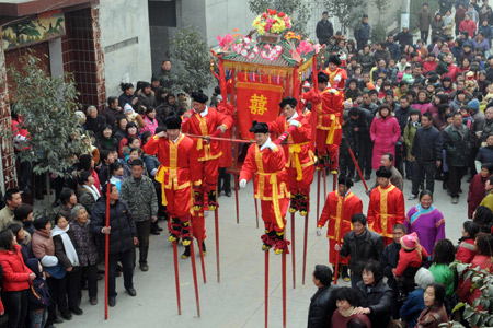 A bride sits in a sedan, carried by people in traditional costume walking on stilts, during a wedding in the Chinese traditional style held at Wannan Village of Qinyang City, central China's Henan Province, Jan. 6, 2009. [Xinhua]