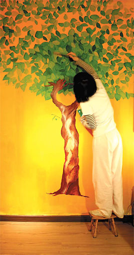 A tree grows under the brush of art designer Chen Lijuan. The painting adds a lively touch to her apartment in Beijing. 