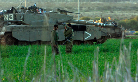 Two Israeli soldiers rest beside the tank in the Gaza Strip Jan. 6, 2009. The Israeli army has said that it would hold fire in the Gaza Strip for three hours every day from Jan. 7 to allow local residents to prepare basic supplies. [Tsafrir Abayov/Xinhua]