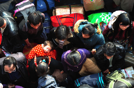 A mother carrying her sleeping baby squeezes with other passengers to enter the Guangzhou Railway Station in Guangzhou, capital of south China's Guangdong Province, Jan. 7, 2009. [Lu Hanxin/Xinhua]