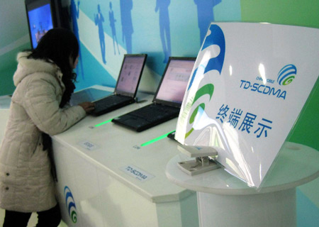  A girl tries the internet functions of a third-generation (3G) mobile phone at a China Mobile exhibition hall in Beijing, China, Jan. 7, 2009. [Xinhua]