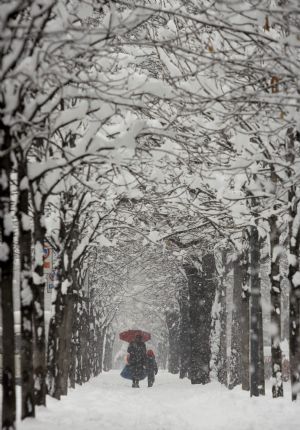 A woman with a child walk in downtown Milan January 7, 2009. Heavy snowfall forced northern Italy to close briefly its major airports on Wednesday, including Malpensa outside Milan. Linate city airport put a halt to flights until early afternoon.[Xinhua]