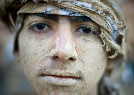  An Iranian man covered in mud looks on while attending the Ashura religious festival in Khorramabad, 491 km (307 miles) southwest of Tehran, Jan. 7, 2009. [Xinhua]