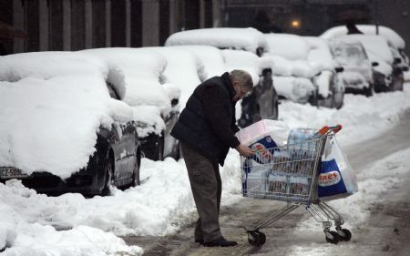 A men tries to push a shopping cart cross a street in Milan January 7, 2009. Heavy snowfall forced northern Italy to close briefly its major airports on Wednesday, including Malpensa outside Milan. Linate city airport put a halt to flights until early afternoon. [Xinhua/Reuters]