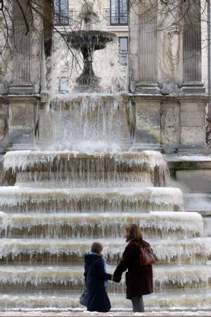 People look at the frozen fountain at the Place des Innocents as winter temperature fall below freezing point in Paris January 7, 2009. [Xinhua/Reuters]