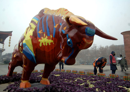 Pedestrians pass one of the two colorful bull statues in Xi'an, capital of northwest China's Shaanxi Province, Jan. 6, 2009. The 5-meter-long, 3-meter-wide and 2.6-meter-high statues were created by Fengxiang folk artists and professors with Xi'an Academy of Fine Arts. [Xinhua] 