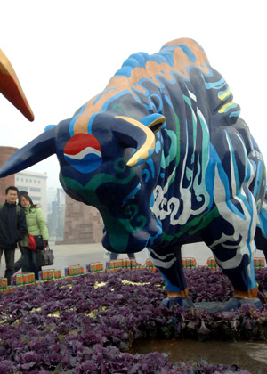 Local residents look at one of the two colorful bull statues in Xi'an, capital of northwest China's Shaanxi Province, Jan. 6, 2009. [Xinhua] 