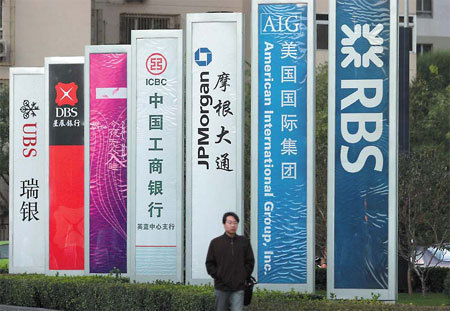A man walks past advertisements of financial institutions on Financial Street in Beijing. [China Daily]
