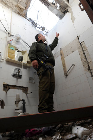 An Israeli soldier inspects the damage to a building caused by Katyusha rockets fired from Lebanon, in Nahariya, northern Israel, Jan. 8, 2009. Several rockets pounded northern Israel Thursday morning, causing light injuries. Israeli forces fought back shortly by firing mortars across the border. [Moran Mayan/Xinhua] 