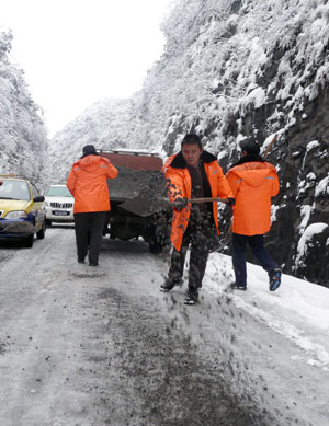 Workers scatter sands on an ice-covered road in Tujia-Miao Autonomous County of Yinjiang, southwest China's Guizhou Province, Jan. 7, 2009. Due to the flow of strong cold air, many regions of Guizhou Province were hit by freezing rain and sleet recently. Workers of road administrative department started to scatter skidproof sands on the frozen road in Tongren area.[Chen Xiaolan/Xinhua]