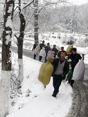 Migrant workers walk in snow on their way home in Tujia-Miao Autonomous County of Yinjiang, southwest China's Guizhou Province, Jan. 7, 2009. Due to the flow of strong cold air, many regions of Guizhou Province were hit by freezing rain and sleet recently. Workers of road administrative department started to scatter skidproof sands on the frozen road in Tongren area.[Chen Xiaolan/Xinhua] 