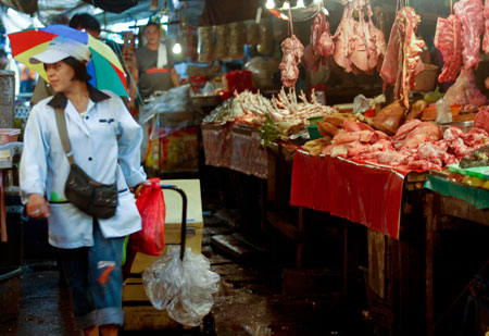 A milk vendor passes by the meat section of a market in Manila, capital of the Philippines, Jan. 8, 2009. A team of international experts is investigating the Ebola Reston virus found in pigs at two farms in the northern Philippines, the World Health Organization (WHO) said on Thursday. [Luis Liwanag/Xinhua]