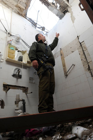 An Israeli soldier inspects the damage to a building caused by Katyusha rockets fired from Lebanon, in Nahariya, northern Israel, Jan. 8, 2009. Several rockets pounded northern Israel Thursday morning, causing light injuries. Israeli forces fought back shortly by firing mortars across the border. [Xinhua] 