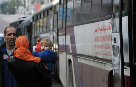 A Palestinian mother and her son with dual citizenship wait outside a bus before they leave the Gaza Strip Jan. 8, 2009.[Xinhua]