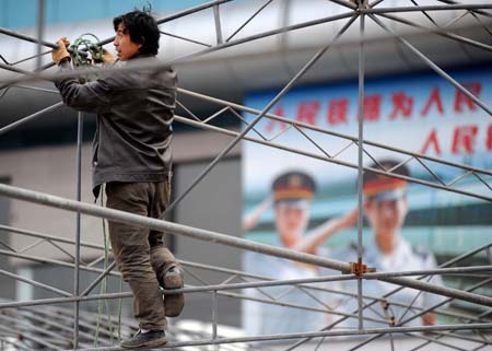 A worker builds the framework of tents to shelter ticket buyers from winter cold at the open ground of the Guiyang Railway Station in Guiyang, capital of southwest China's Guizhou province, Jan. 7, 2009, prior to the Chinese lunar New Year starting from Jan. 26. Hundreds of millions of Chinese people are expected to move around by means of railway during the lunar New Year holidays. [Wu Dongjun/Xinhua]