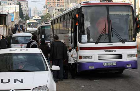  A Palestinian family with dual citizenship stands outside a bus before they leave the Gaza Strip Jan. 8, 2009. [Wissam Nassar/Xinhua]