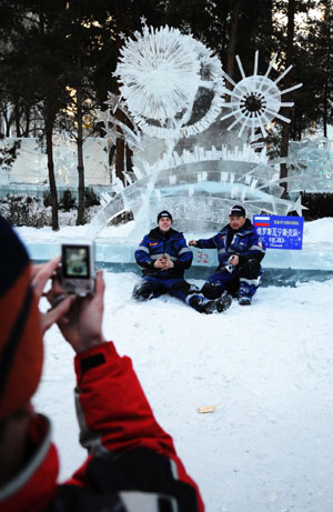 Two competitors pose for photos in front of their ice sculpture during the 23rd International Ice Sculpture Competition in Harbin, Northeast China's Heilongjiang Province, January 8, 2009. About 60 competitors from 12 countries and regions took part in this event which concluded on Thursday. [Xinhua] 