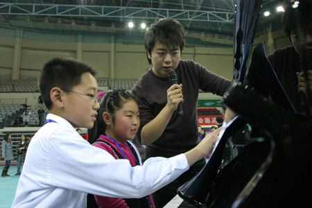 Chinese piano prodigy Lang Lang gives children instruction in playing piano in Tianjin, north China, Jan. 8, 2009. The famous young Chinese pianist Lang Lang conducted a piano ensemble performance given by one hundred children studying piano in Nankai University on Thursday. [Li Xiang/Xinhua] 