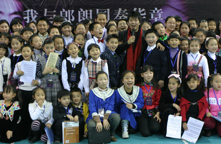 Chinese piano prodigy Lang Lang poses for group photo with children in Tianjin, north China, Jan. 8, 2009. The famous young Chinese pianist Lang Lang conducted a piano ensemble performance given by one hundred children studying piano in Nankai University on Thursday. [Li Xiang/Xinhua]
