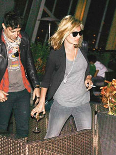 Kate Moss (R), escorted by boyfriend Jamie Hince, has a cup of champagne on one hand and a cigarette on the other at a bar in Hong Kong Central on Wednesday, January 7, 2009.