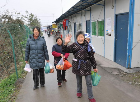 People return their temporary home with groceries at a housing area for May 12 earthquake survivors in Dujiangyan, southwest China's Sichuan province January 6, 2009. 