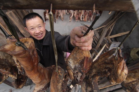 A man hangs preserved hams to the roof beam of his house in preparation for the Chinese Lunar New Year in Yong'an town, Beichuan county, a hard-hit area by the May 12 earthquake in Southwest China's Sichuan province, January 6, 2009. 