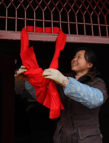 A woman hangs a red ribbon on the doorway of her newly built house in Yong'an twon, Beichuan county, southwest China's Sichuan province January 6, 2009. 