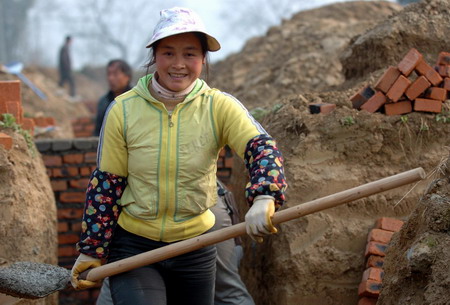 A woman shovels cement to bulid houses in Banqiao town, Qingchuan county, Southwest China's Sichuan province January 6, 2009. More than 46,000 homes will be finished for the May 12 quake survivors in the county within 2009 with the money donated by people in Zhejiang province.
