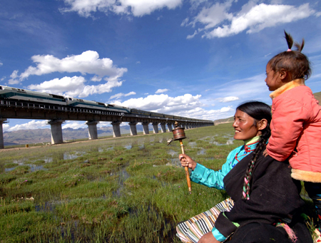 Local residents look on as a train passes through the Qinghai-Tibet railway in Damxung county, Tibet, in this file photo. [Xinhua]
