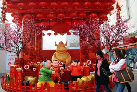 Pedestrians walk past a decoratin celebrating the Spring Festival, or the Chinese lunar New Year, which falls on Jan. 26 this year, in Shanghai, east China, Jan. 9, 2009. [Xinhua]