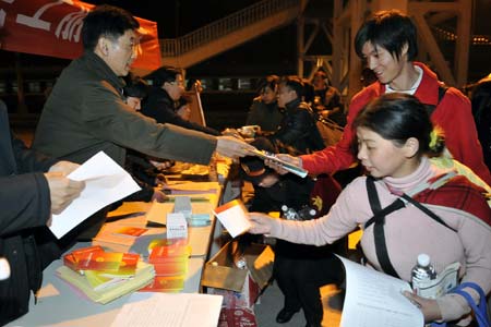 Staff members of the Yichang General Labor Union distribute bottled water and employment manual to migrant workers at the Yichang Railway Station in Yichang, central China's Hubei Province, Jan. 10, 2009. The first train specifically for migrant workers arrived in Yichang from Guangzhou, capital of south China's Guangdong Province, on Saturday, carrying more than 2,000 migrant workers.[Xinhua] 