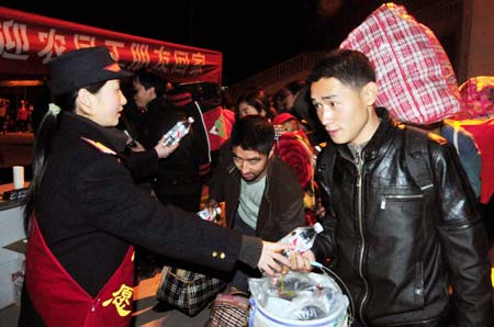 Staff members of the Yichang General Labor Union distribute bottled water and employment manual to migrant workers at the Yichang Railway Station in Yichang, central China's Hubei Province, Jan. 10, 2009. The first train specifically for migrant workers arrived in Yichang from Guangzhou, capital of south China's Guangdong Province, on Saturday, carrying more than 2,000 migrant workers.[Xinhua]