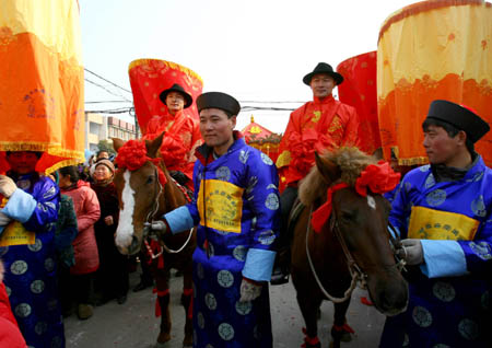 Bridegrooms Li Guanglong and Li Guangbiao, who are twins, ride horses during a wedding ceremony in the Chinese traditional manner in Donghai County, east China's Jiangsu Province, Jan. 11, 2009.[Zhu Guilin/Xinhua]