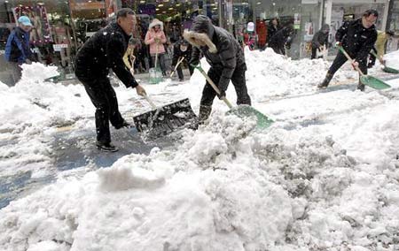 People shovel snow on a street in Jeongeup, about 280 km (174 miles) south of Seoul, after heavy snowfall, January 12, 2009. [Xinhua/Reuters]