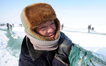 A fisherman drags the fishing net on the Ulunggur Lake in Fuhai County, northwest China's Xinjiang Uygur Autonomous Region, Jan 8, 2009. The traditional winter halieutics here bring considerable incomes to local fishmen, and boosts the tourism around the Ulunggur Lake as well. [Sadat/Xinhua]