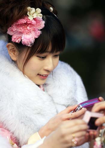 A Japanese twenty-year-old girl dressed in traditional kimonos looks at her digital camera after attending a ceremony to celebrate the annual Coming-of-Age Day at the Tokyo Disneyland in Urayasu City of Chiba Prefecture, suburban Tokyo, on Jan. 12, 2009.[Xinhua]