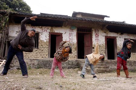 Xu Zhenguang (1st L), does setting-up exercises with 3 pupils during a break at the four-person primary school of Siliu Village in Rongshui County, southwest China&apos;s Guangxi Zhuang Autonomous Region, Jan. 12, 2009. Only 3 pupils were still attending the school while others left with their migrant-worker parents in recent years. Mr. Xu, who has been a teacher for 37 years, stuck to his job at the four-person school. (Xinhua/Long Tao)